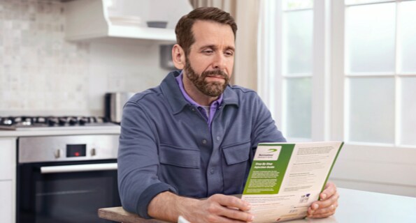 Middle-aged white male in blue jacket reviewing Serostim® Step by Step Injection Guide, not actual patient