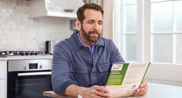 Middle-aged white male in blue jacket reviewing Serostim® Step by Step Injection Guide, not actual patient