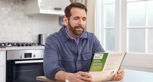 Middle-aged white male in blue jacket reviewing Serostim® Step by Step Injection Guide, not actual patient